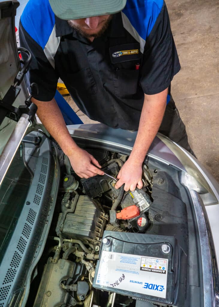 A Robert Jr's Tire & Auto employee is installing a car battery.